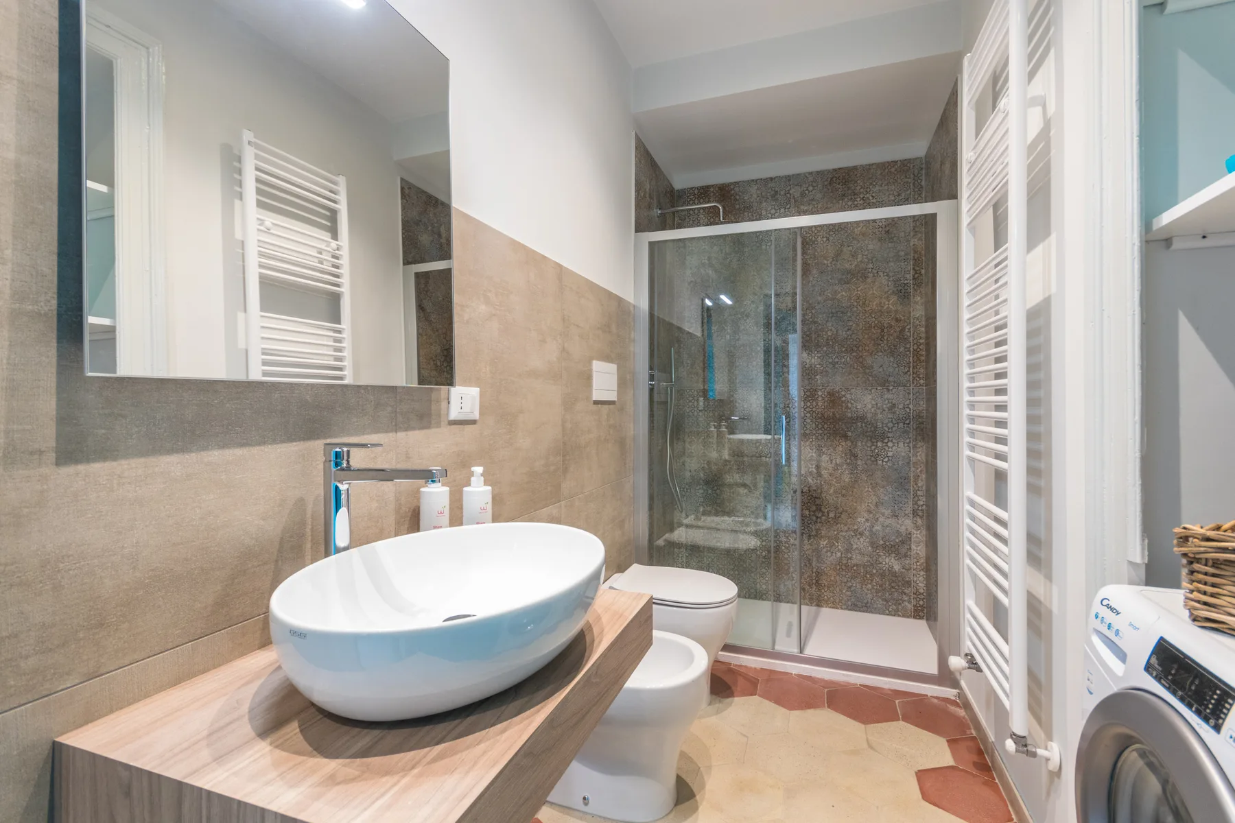 A bathroom with a vessel sink, toilet, and glass shower.