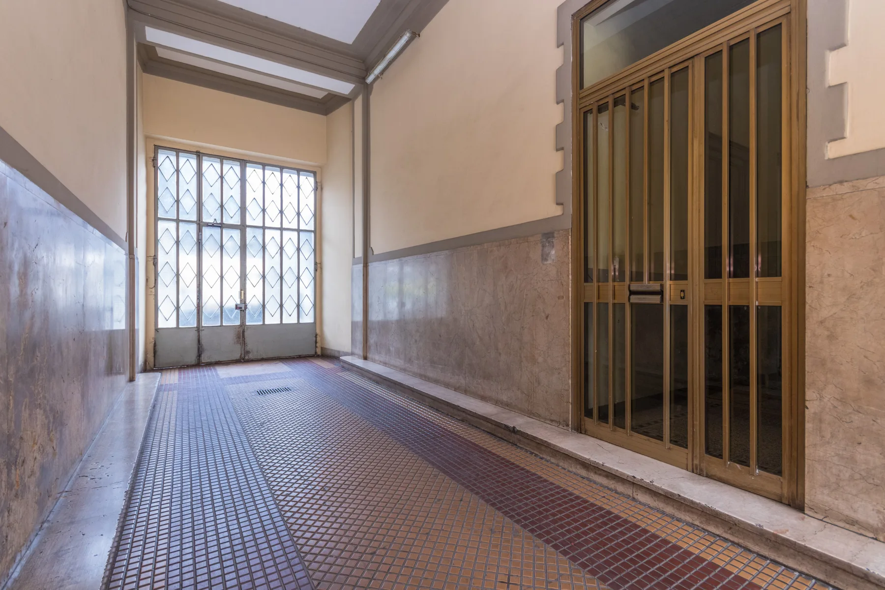 A tiled entry corridor with barred windows and a metal gate.