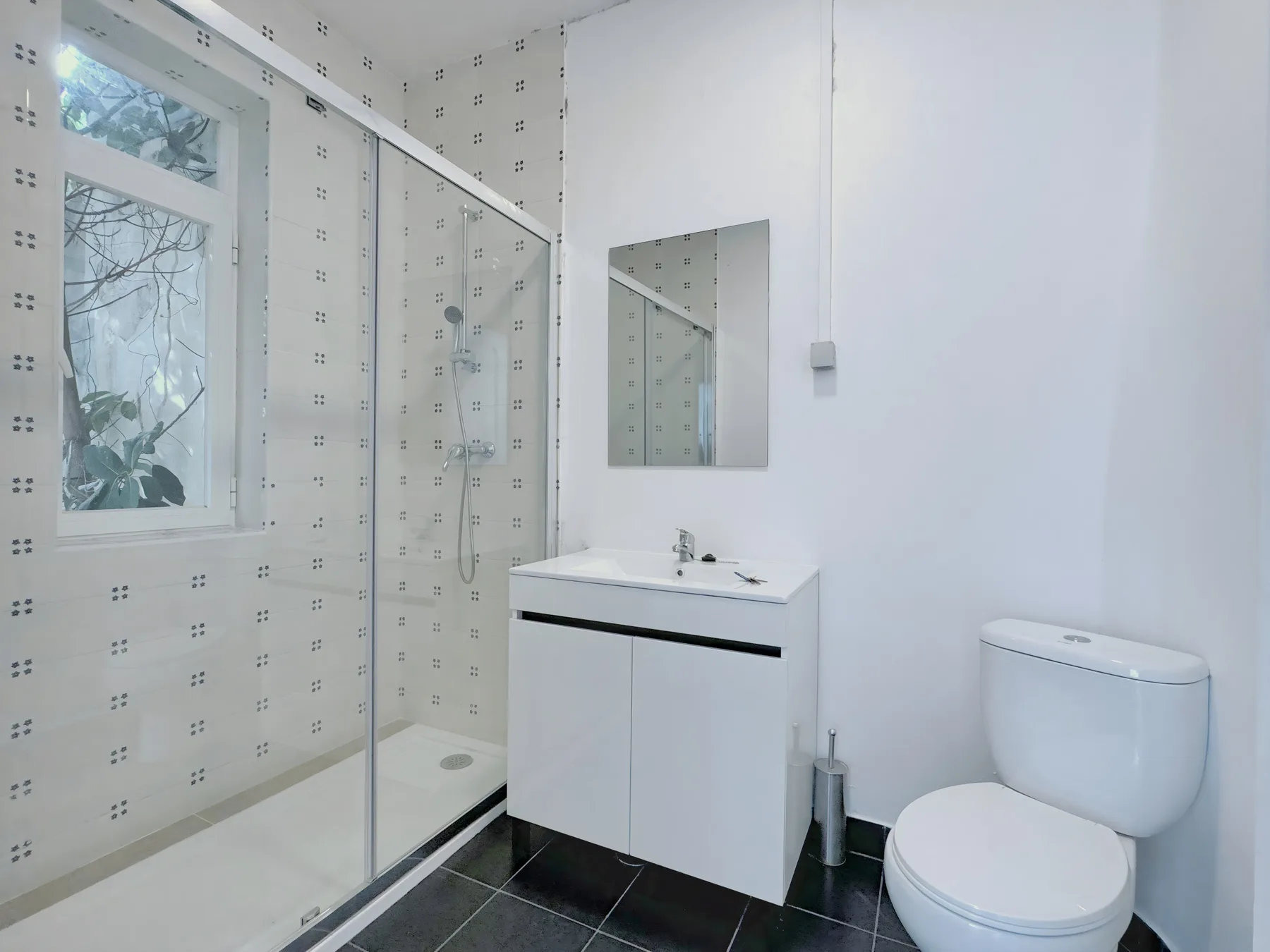 A bright bathroom with a glass shower, vanity, and toilet.