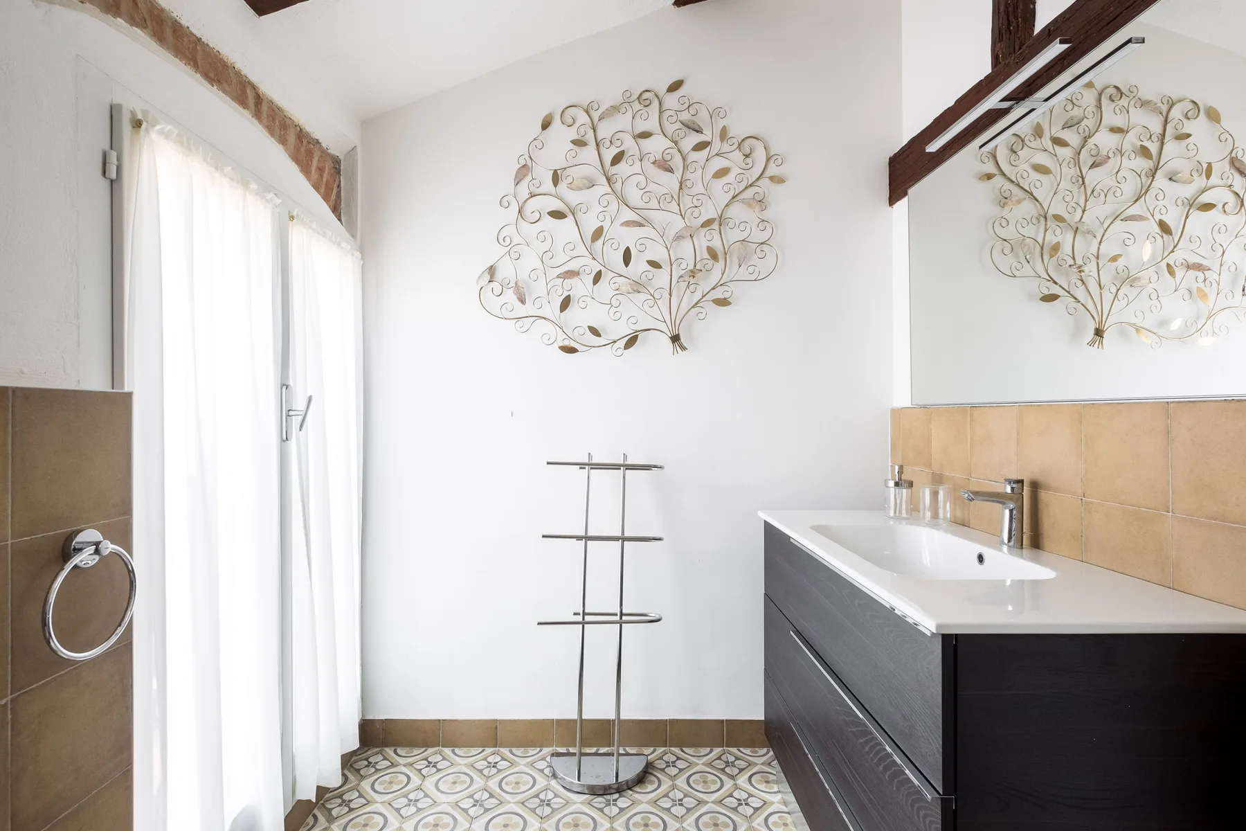 A bright bathroom with a shower curtain, vanity, and decorative wall art.