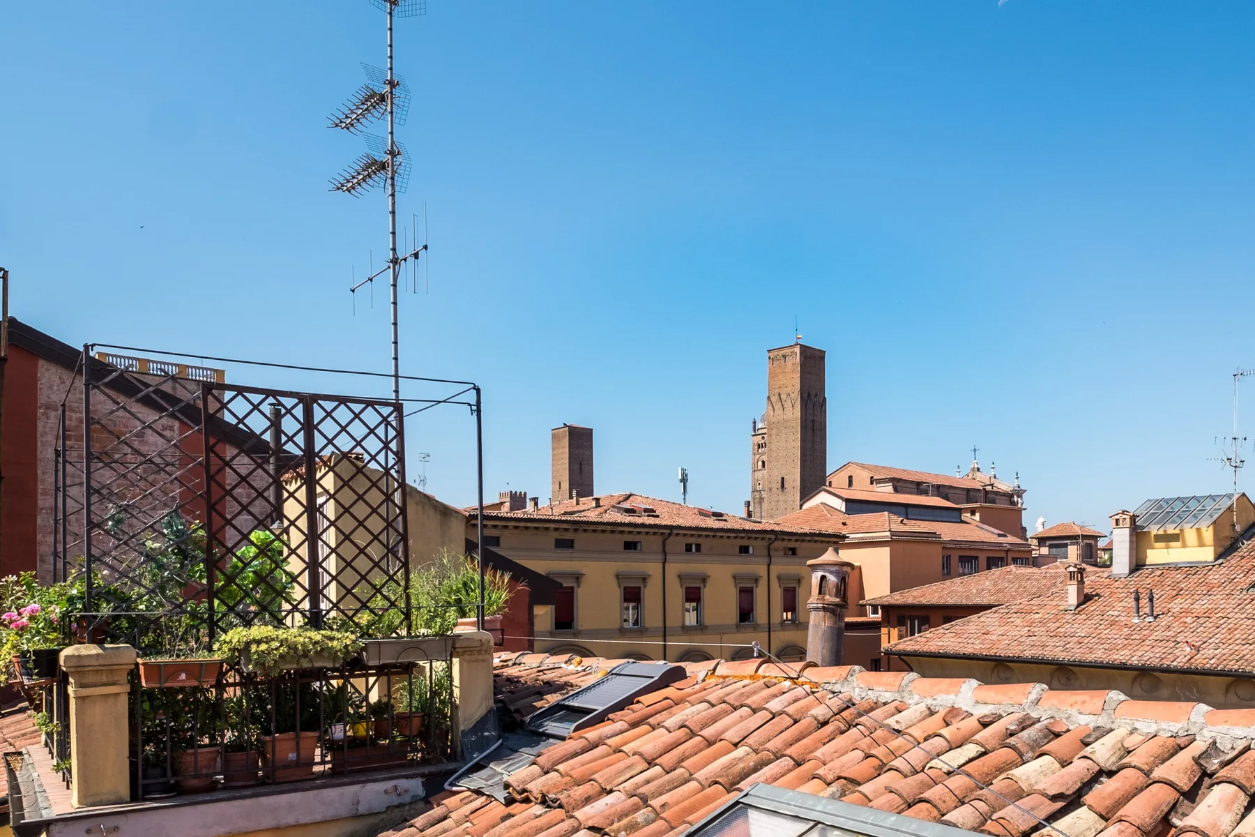 Terraza en la azotea con vistas a tejados de terracota y edificios históricos bajo un cielo despejado.