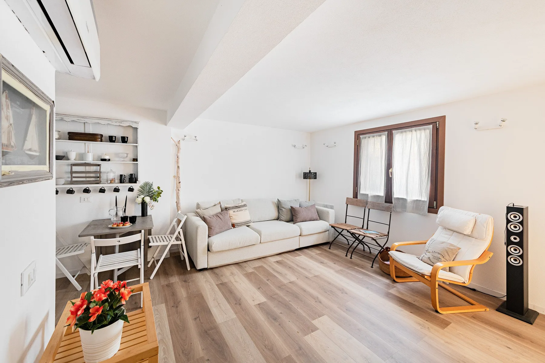 A bright living room with seating, a small dining table, and large windows.