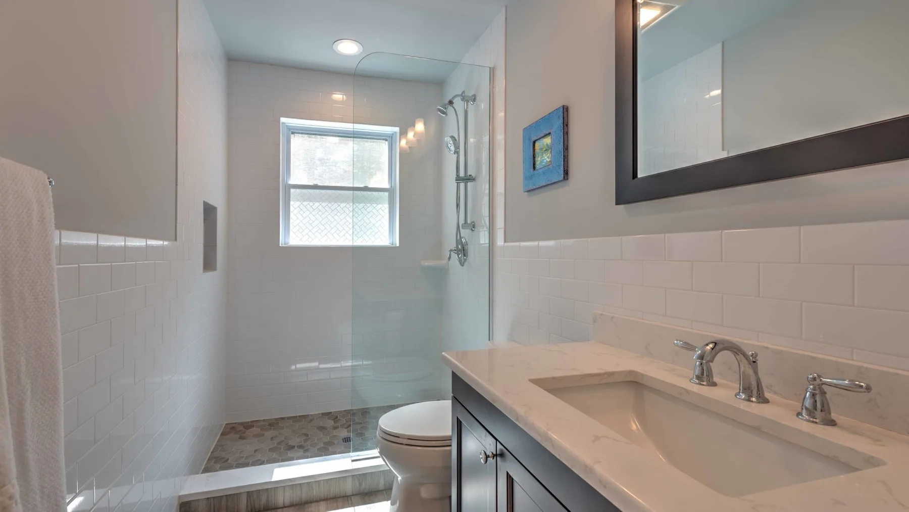 Un baño luminoso con ducha de vidrio, ventana y lavabo.