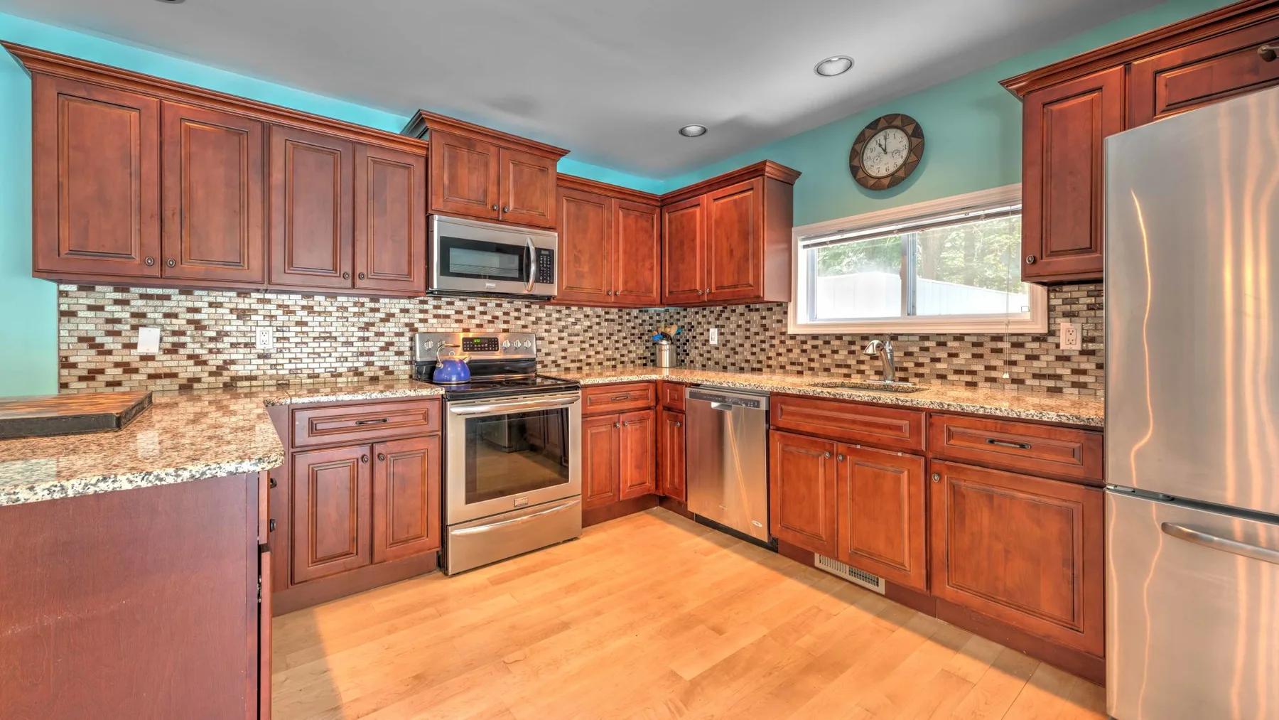 Una cocina con gabinetes de madera, un salpicadero de azulejos y electrodomésticos de acero inoxidable.