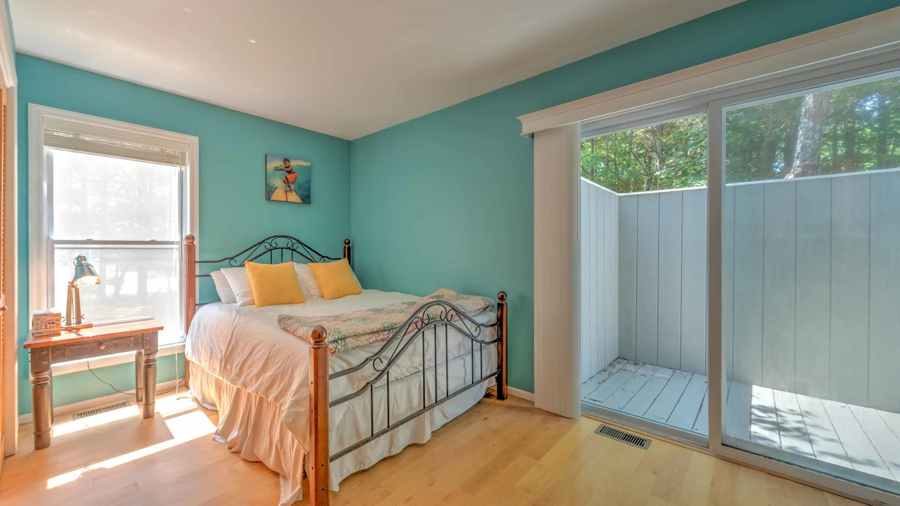 Un dormitorio con una cama, una mesa auxiliar y puertas corredizas de vidrio que dan a un pequeño espacio exterior.