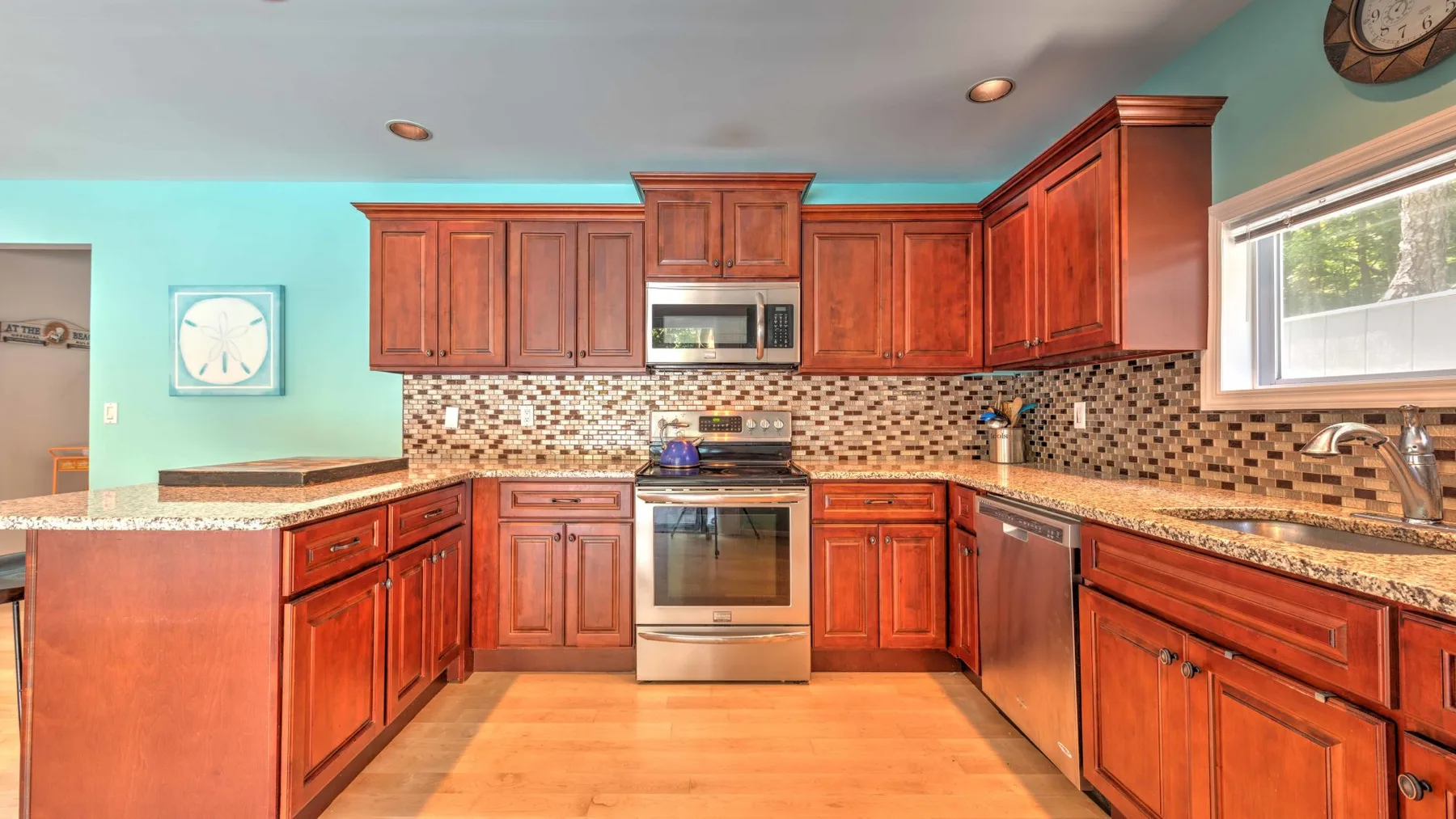 Una cocina con gabinetes de madera, salpicadero de azulejos y una ventana sobre el fregadero.