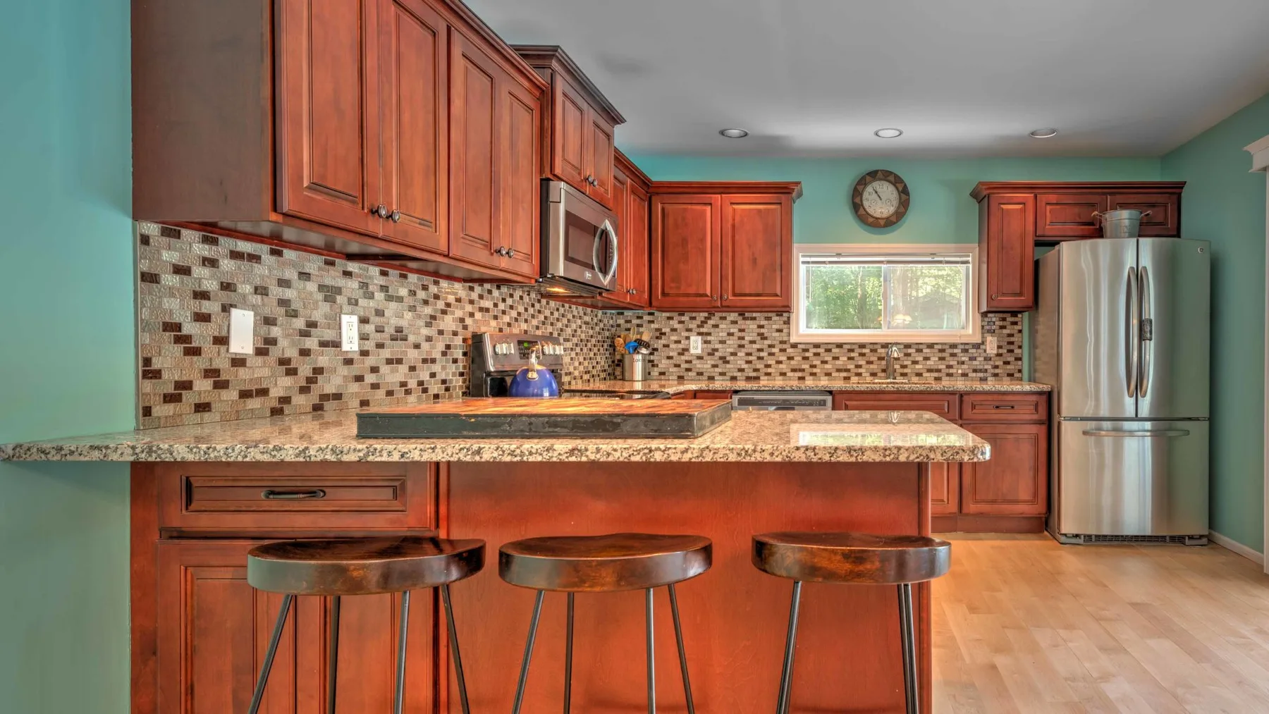 Una cocina con gabinetes de madera, un salpicadero de azulejos y una isla con asientos.