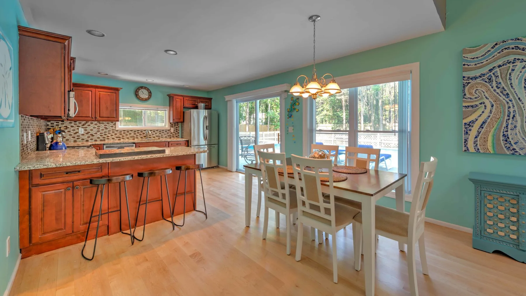 Una cocina abierta y zona de comedor con una mesa junto a grandes ventanas.