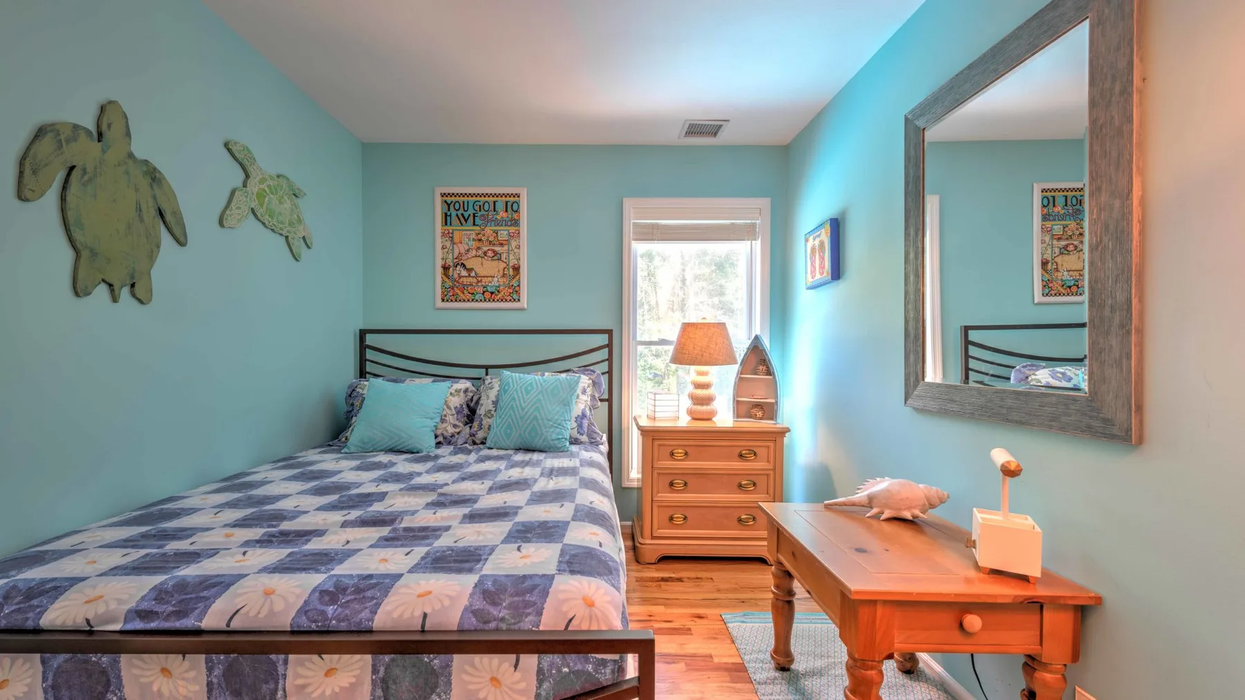 Un dormitorio con una cama, una cómoda de madera y un pequeño escritorio.
