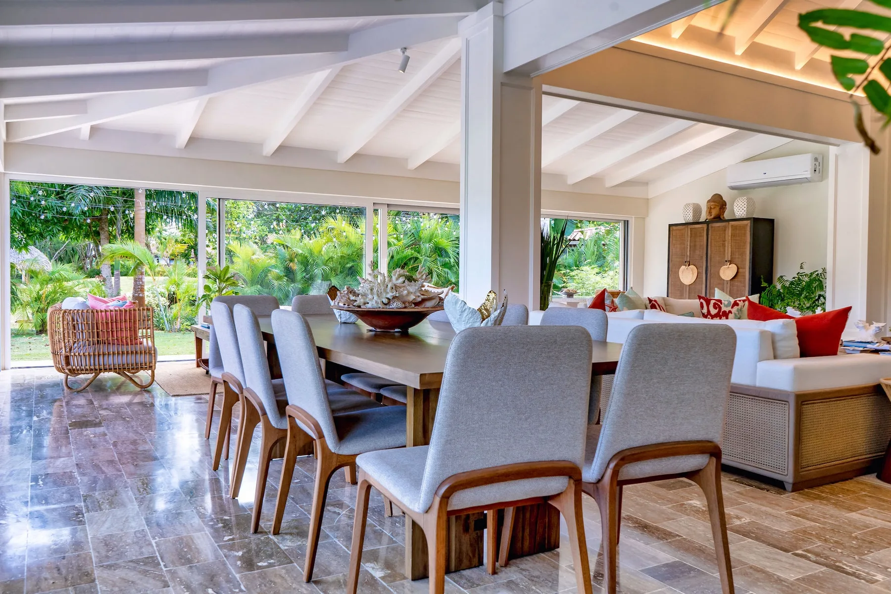 An open-plan dining and living area has large windows overlooking greenery.