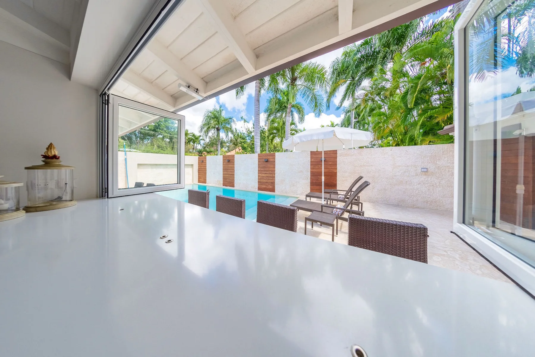 A covered patio with outdoor seating overlooks a courtyard surrounded by palm trees.