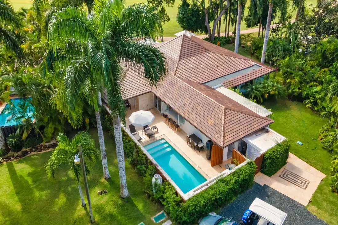 An aerial view of a tropical villa with a swimming pool and surrounding greenery.
