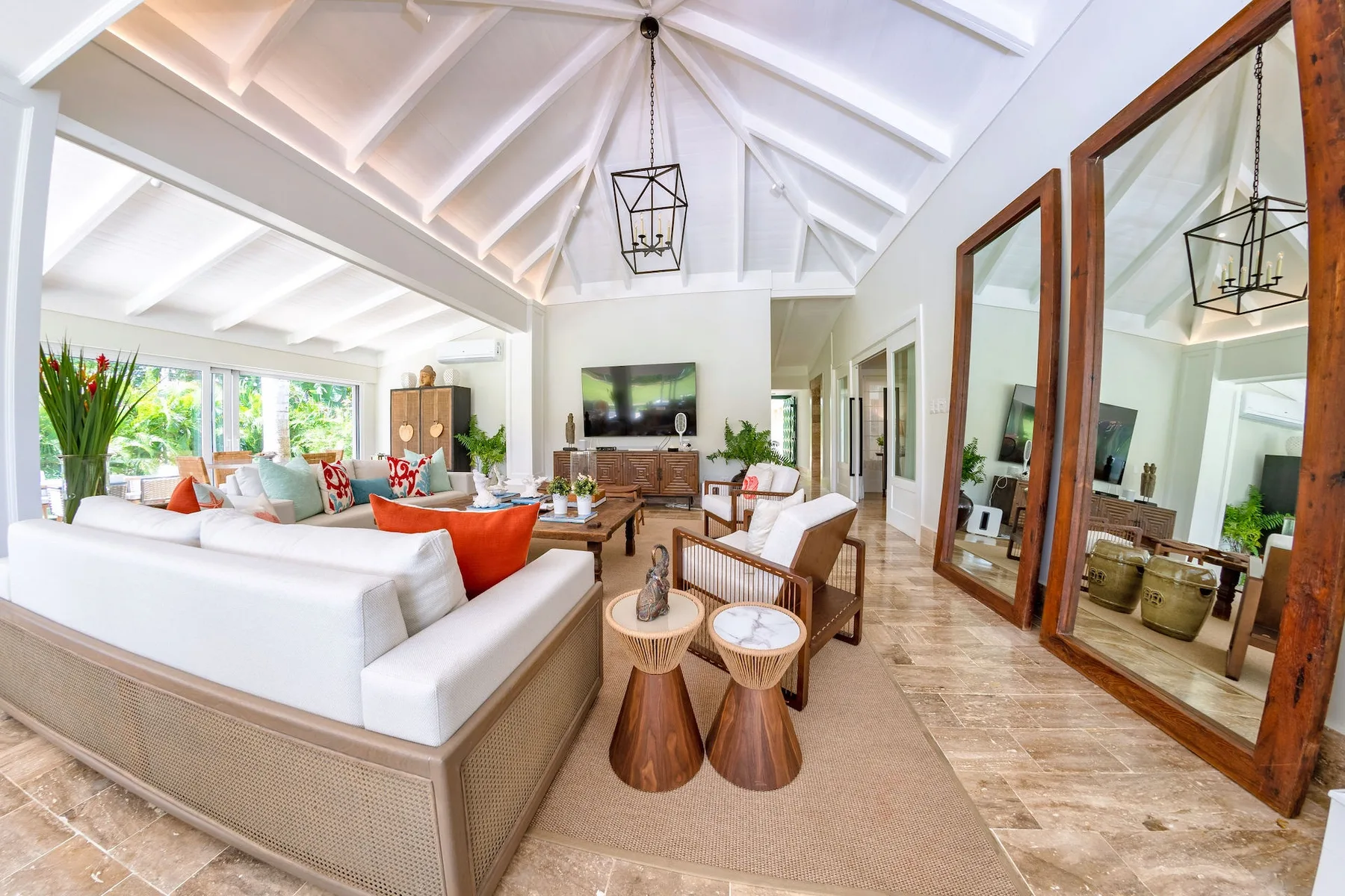 A bright living room with a high vaulted ceiling and seating around a television.