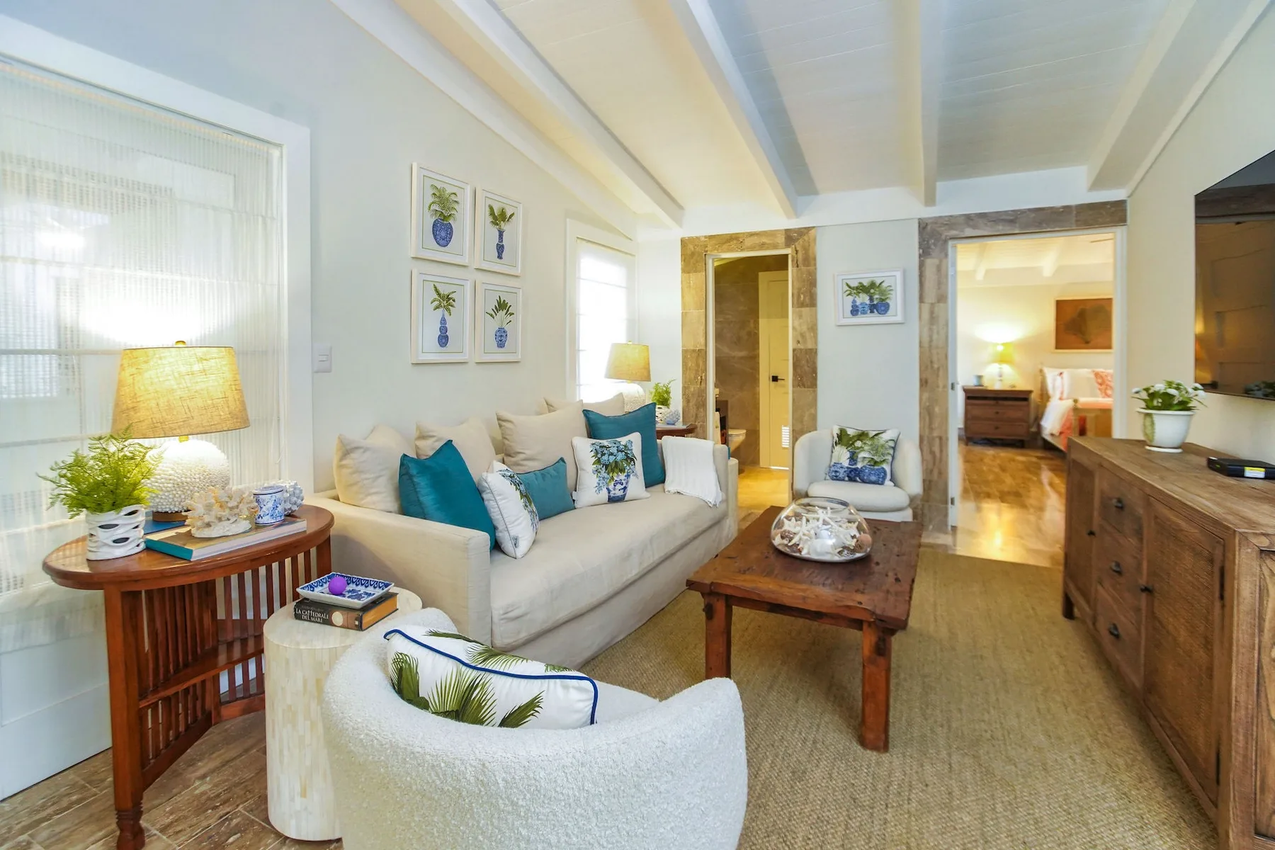 A bright living room with seating, a wooden coffee table, and framed wall art.