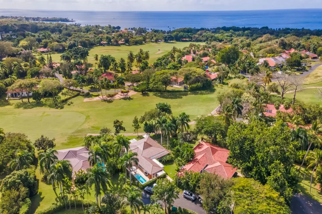 Aerial view of homes and landscaped grounds beside a broad body of water.