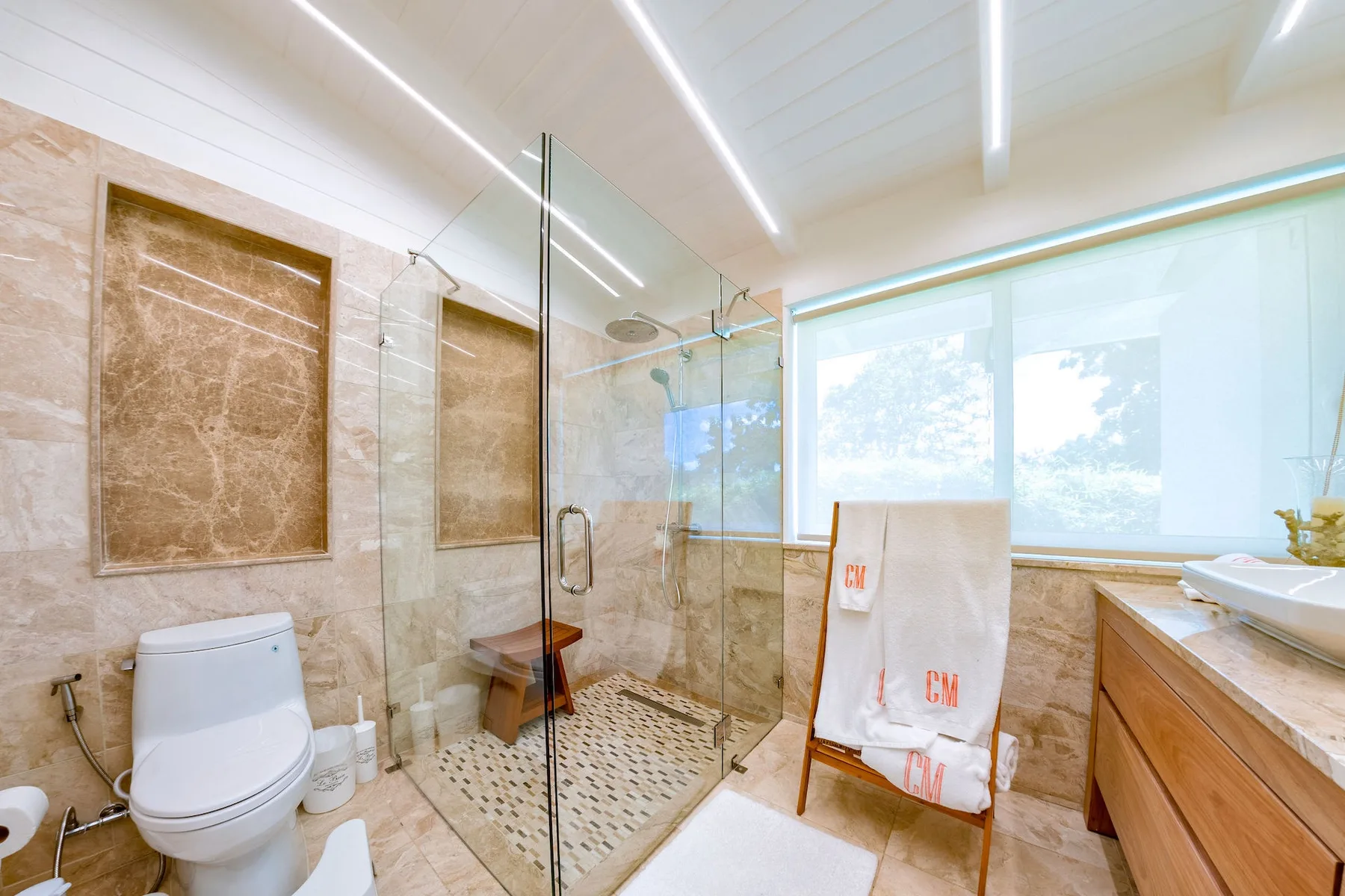 A bright bathroom with a glass shower and a large window.