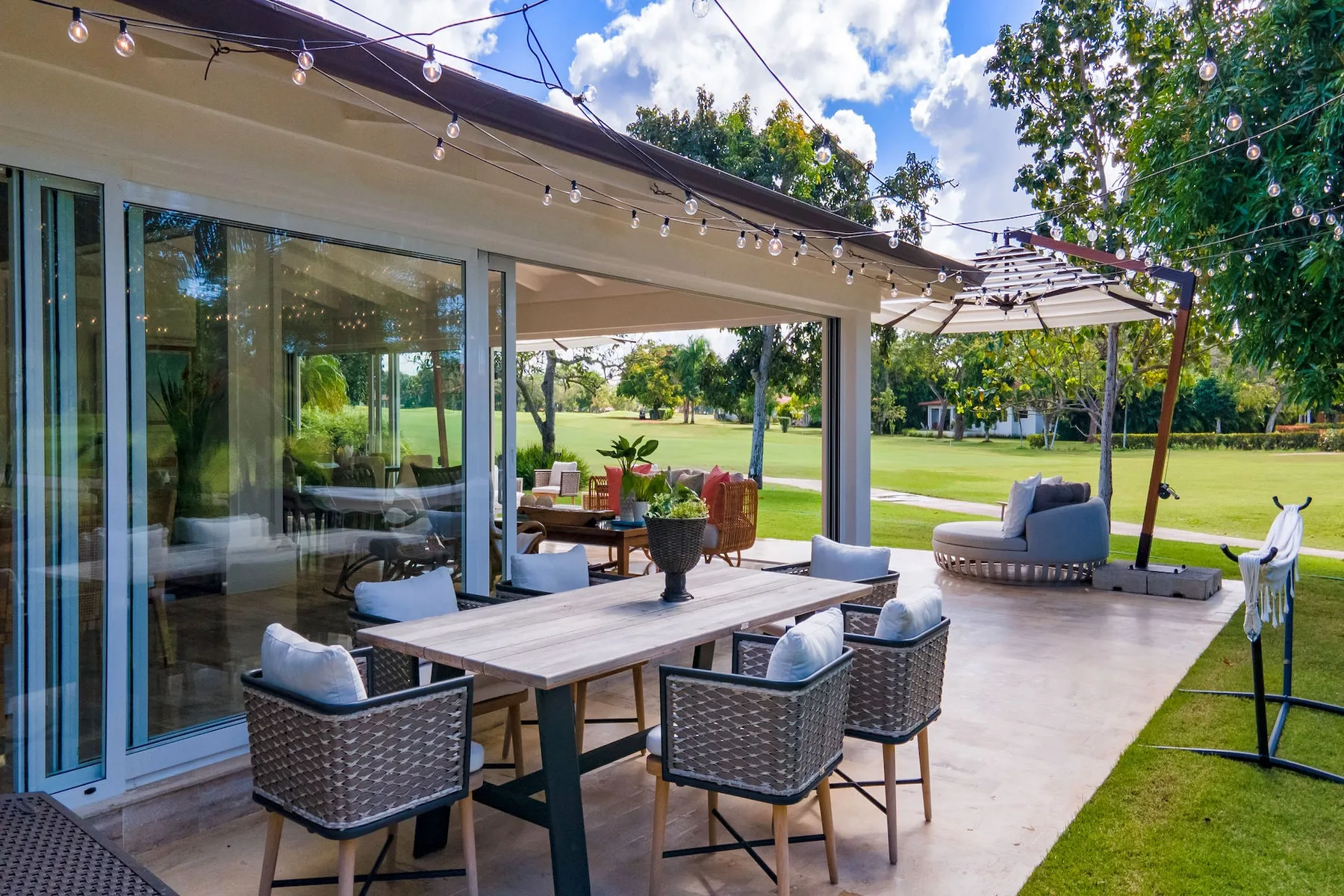 Un patio cubierto con muebles de comedor y una zona de estar junto al césped.