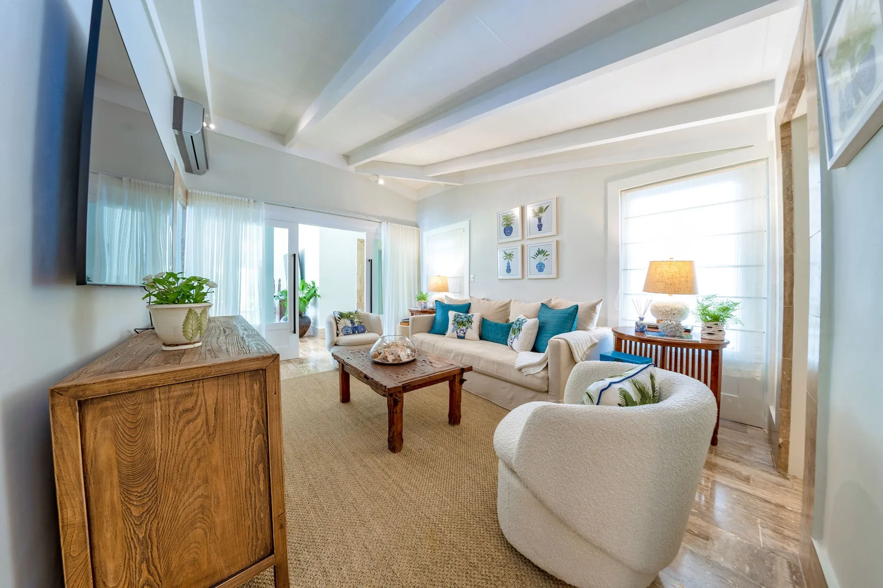 A bright living room with seating, a coffee table, and large windows.