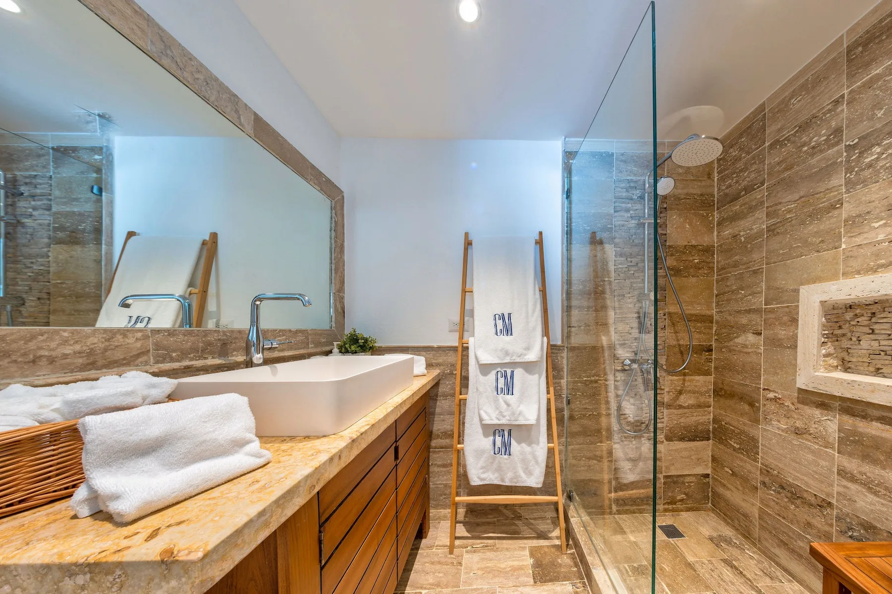 A bathroom with a long vanity, sink, and glass shower.