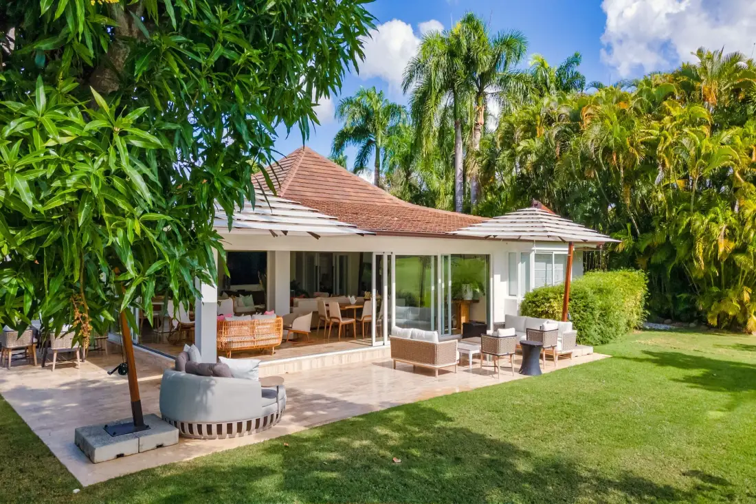 Una casa se abre a un patio con asientos al aire libre y césped verde.