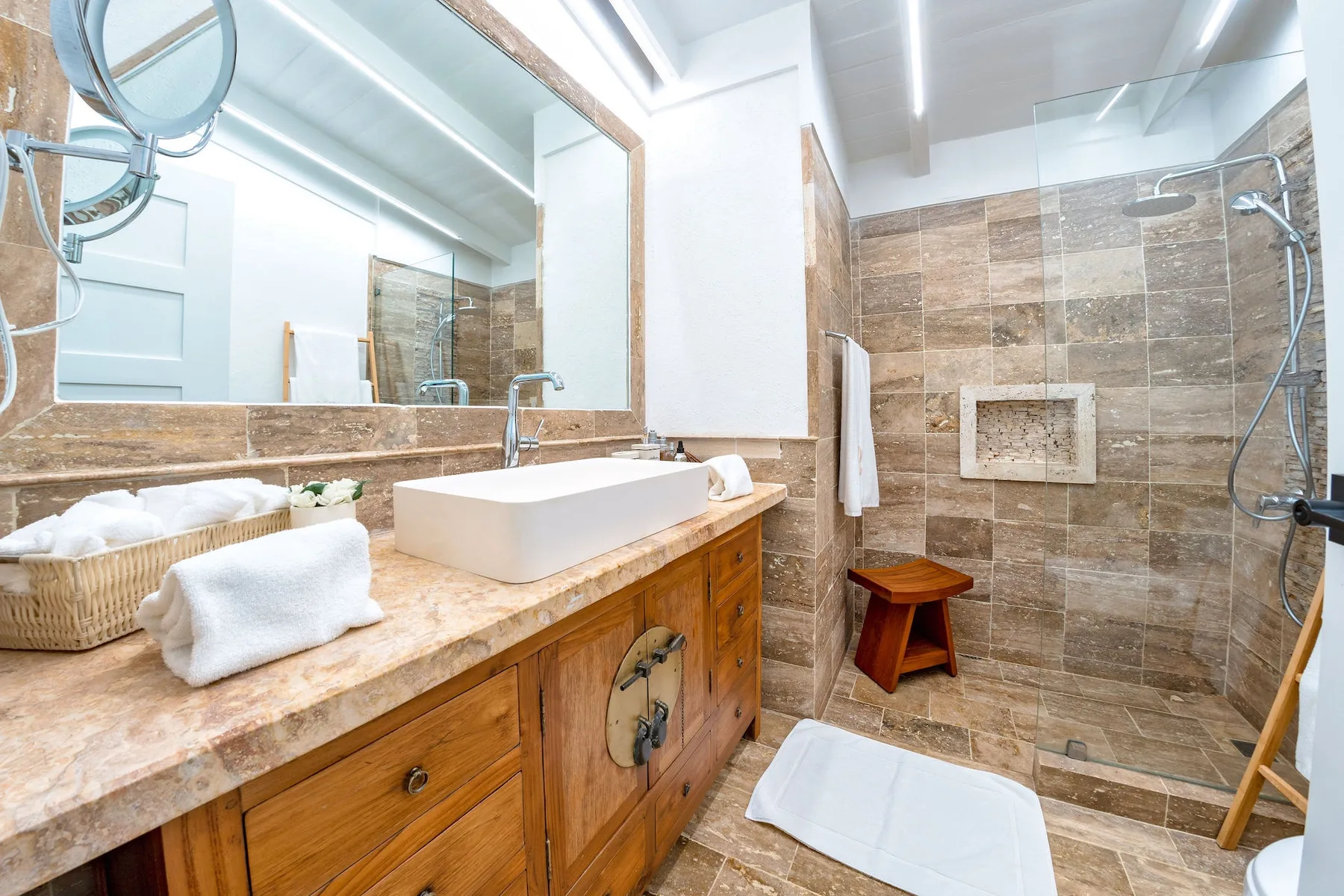 A bathroom with a sink vanity and a glass-enclosed shower.