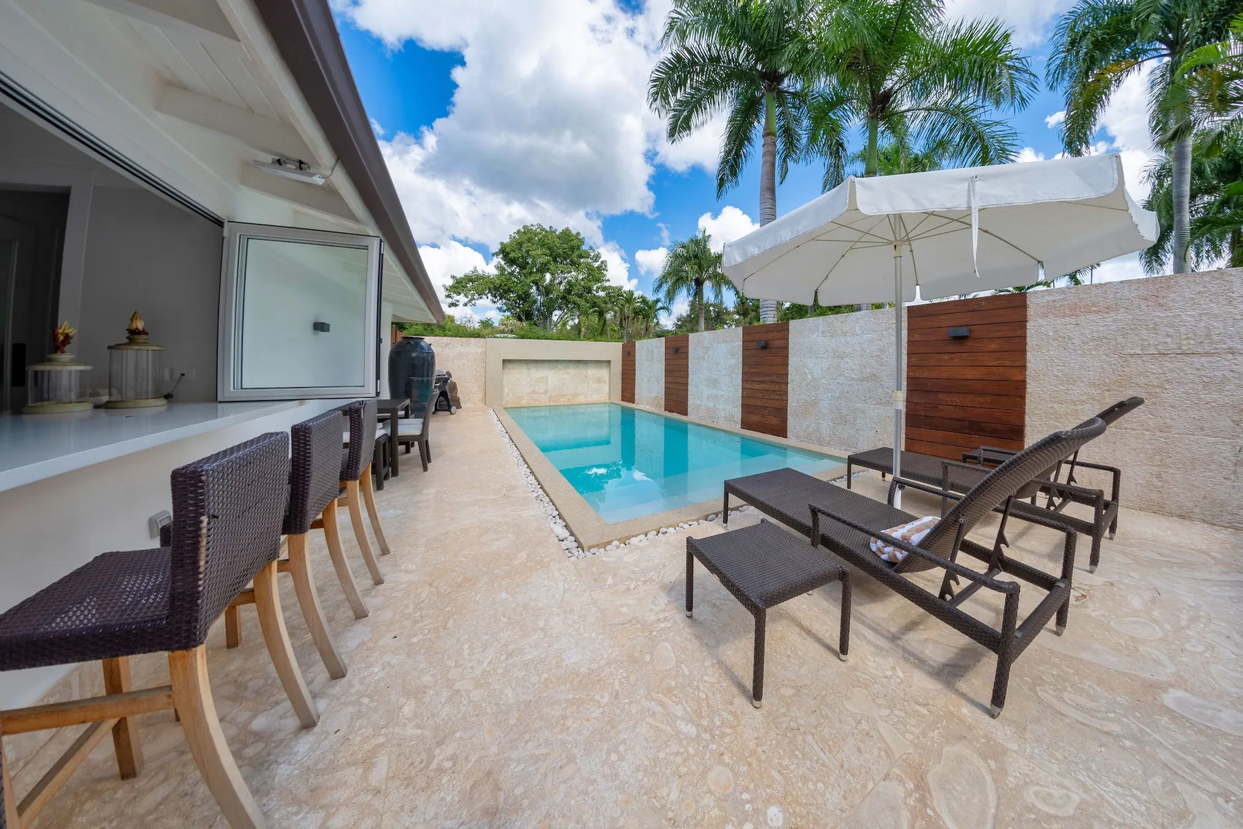 An outdoor pool patio with lounge seating and a large umbrella.