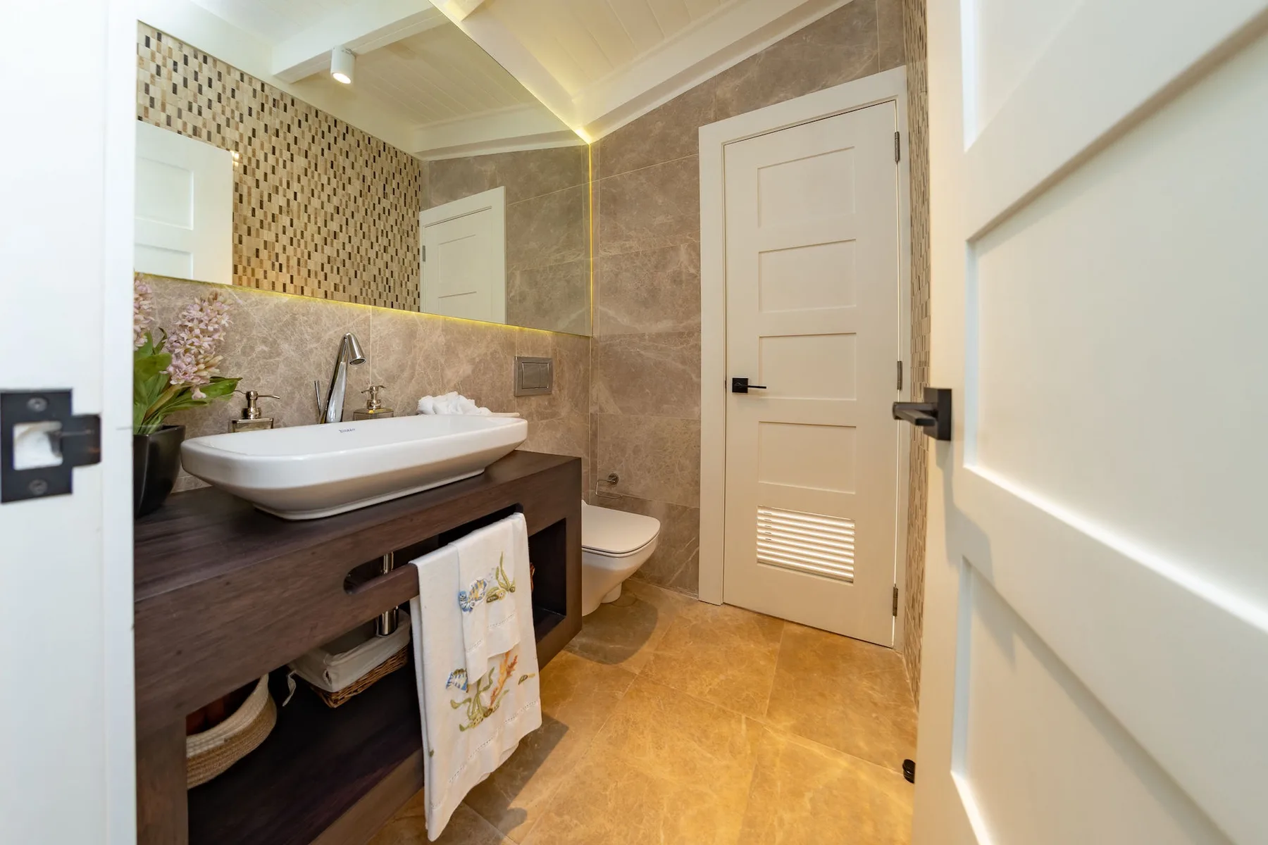 A bathroom with a sink, vanity, and tiled walls.