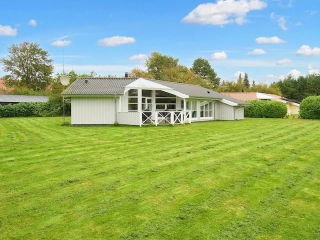 A single-story house with a covered porch stands beside a broad green lawn.