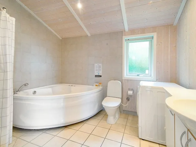 A bright bathroom with a large bathtub, toilet, and vanity.