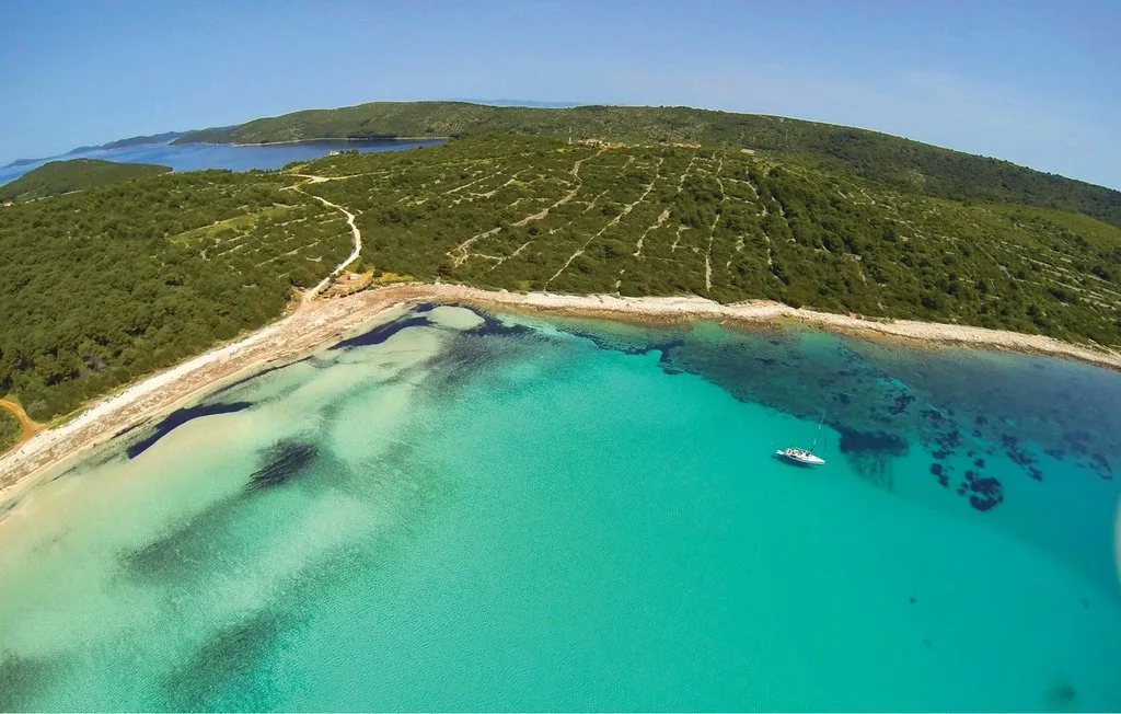 Vista aérea de una bahía turquesa junto a una costa verde y boscosa.
