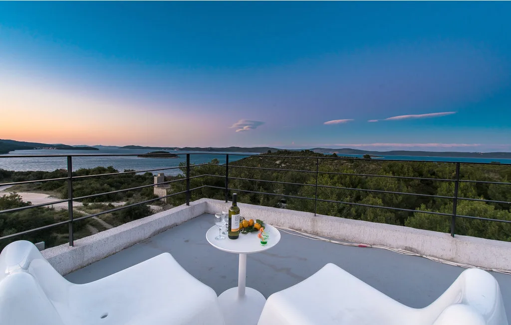 Una terraza en la azotea da al agua, con asientos y una mesa pequeña.