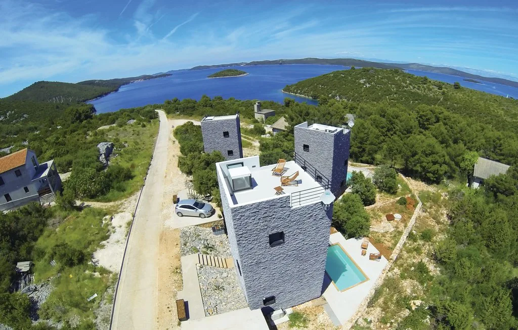 Vista aérea de edificios modernos entre colinas verdes junto a un mar azul.