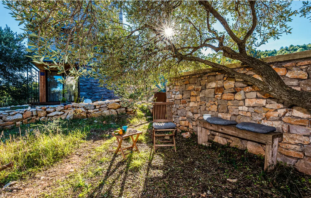Un patio de piedra a la sombra, con asientos al aire libre bajo un árbol frondoso.