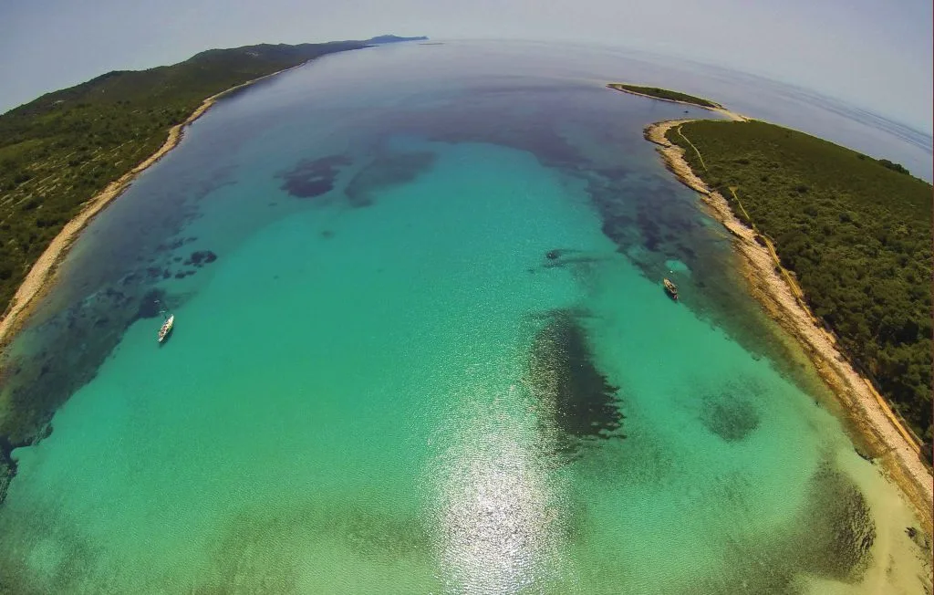 Vista aérea de aguas turquesas entre dos costas verdes.