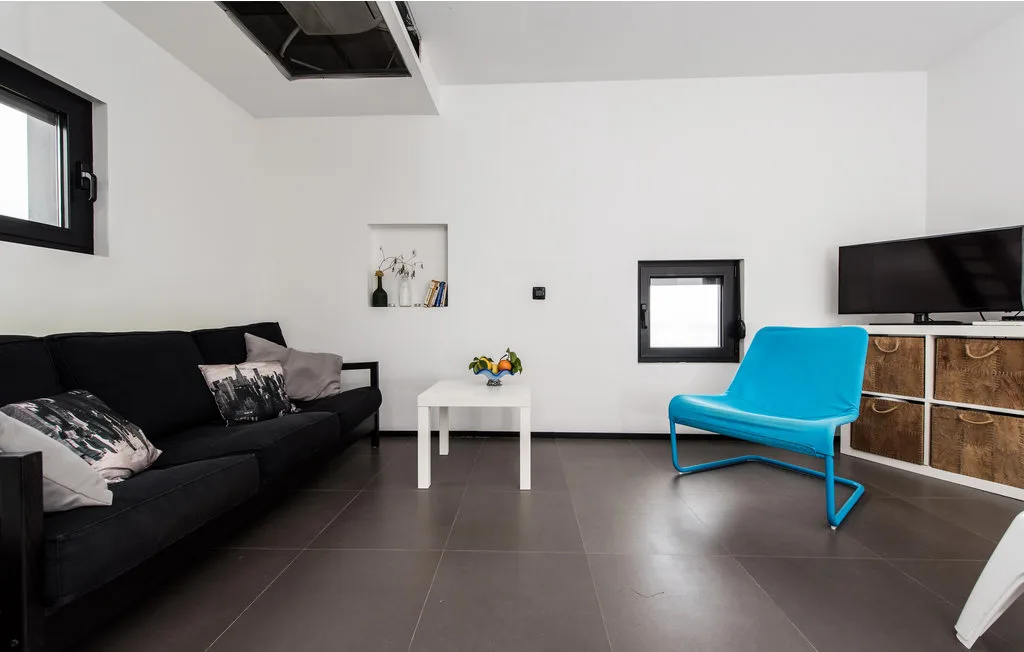 Una sala de estar moderna con asientos oscuros, una mesa de centro y una silla azul.