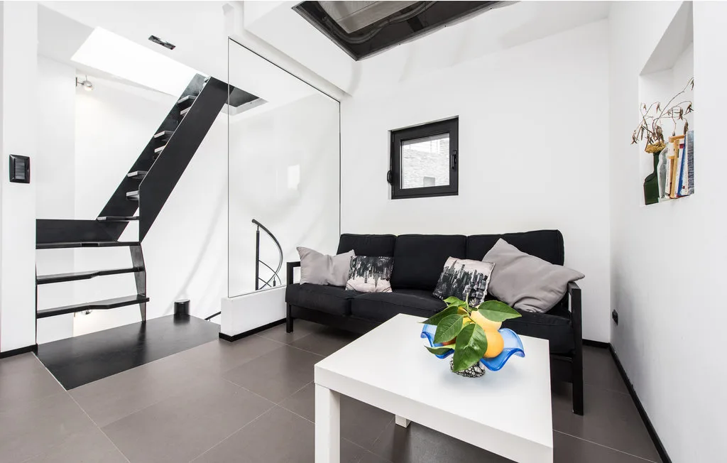Una sala luminosa con asientos oscuros, una mesa blanca y una escalera.