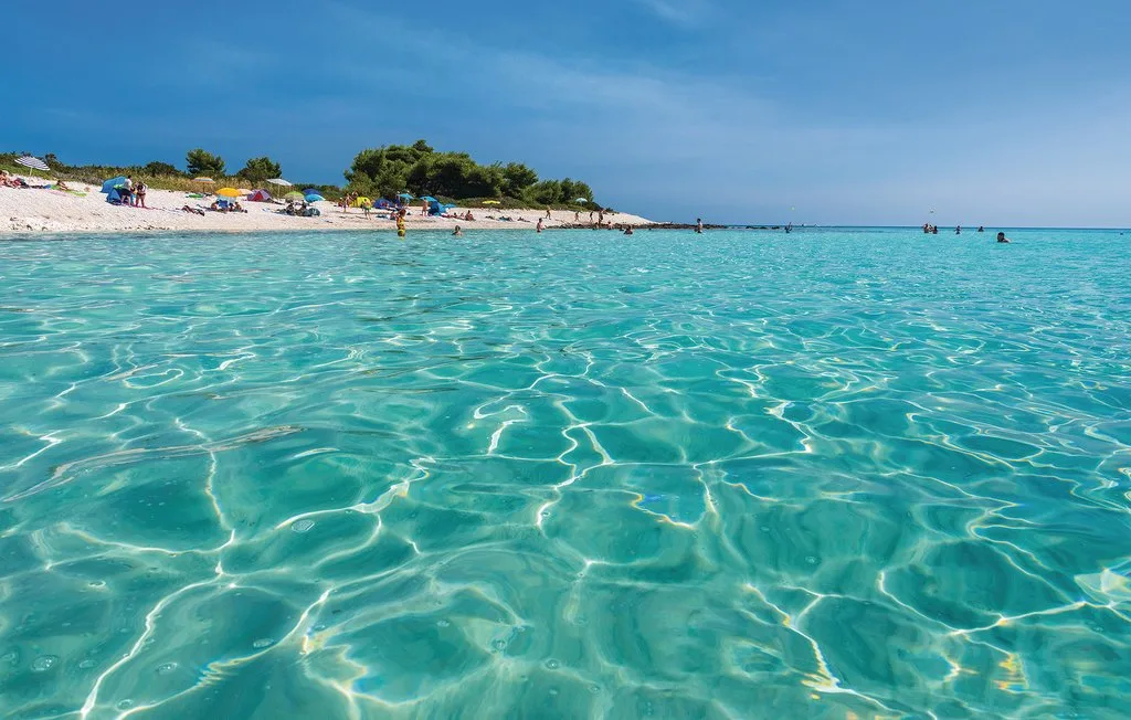 Una playa con agua turquesa clara y una orilla de arena.