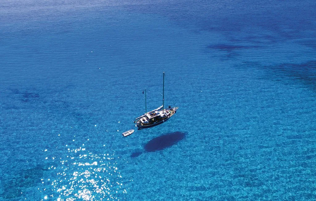 Un velero flota sobre aguas azules y claras.