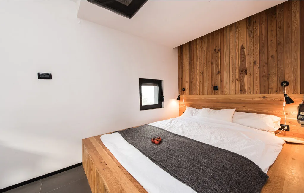 Un dormitorio con una cama grande y una pared revestida de madera.