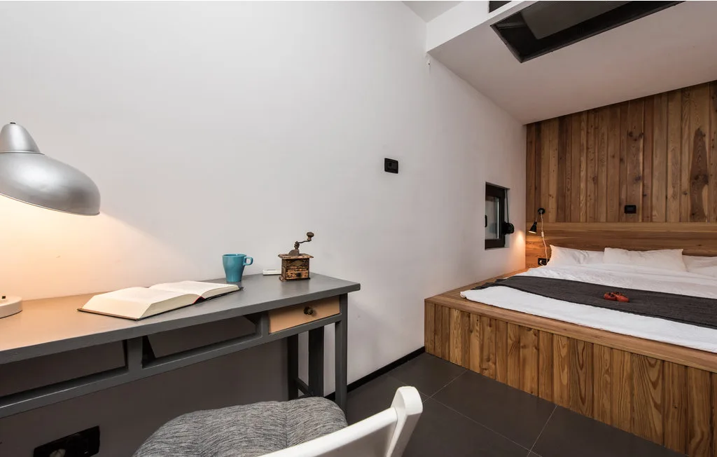 Un dormitorio con un escritorio junto a una cama frente a una pared revestida de madera.