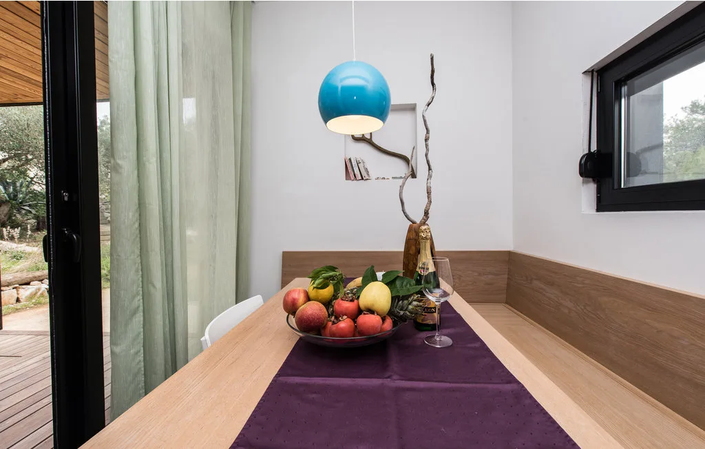Una mesa de comedor con un camino morado y un frutero está junto a una puerta de vidrio.