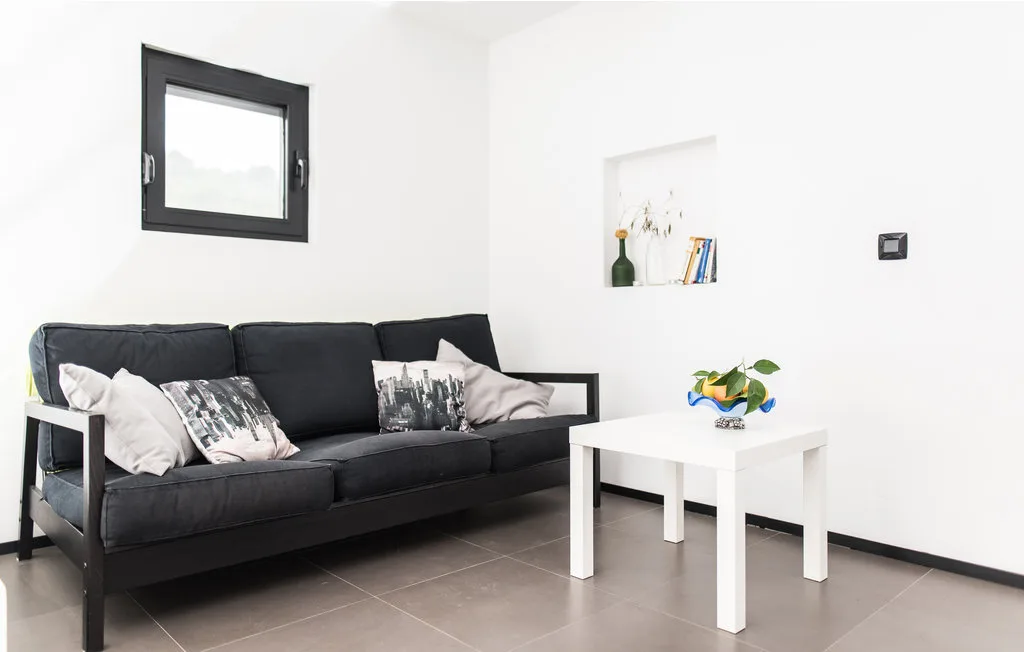 Una sala de estar con asientos oscuros y una mesa de centro blanca.