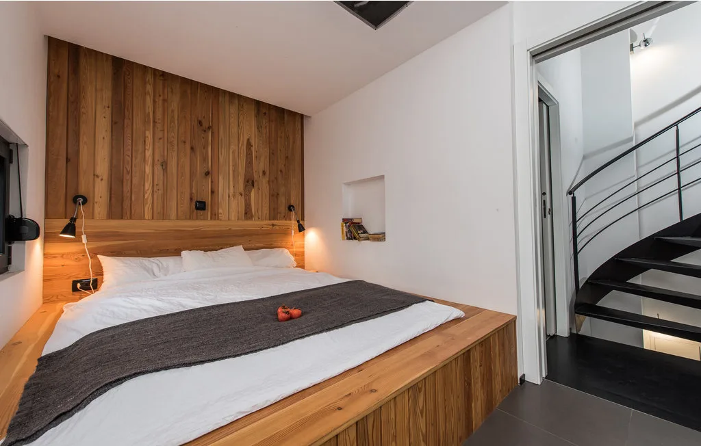 Un dormitorio con una cama bajo un panel de madera, junto a una escalera.