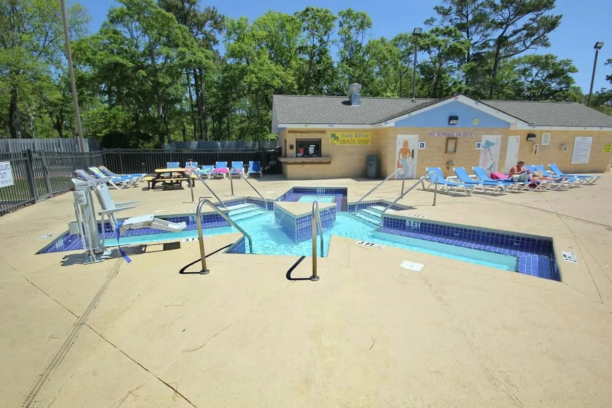Una piscina al aire libre con tumbonas azules junto a un edificio bajo.