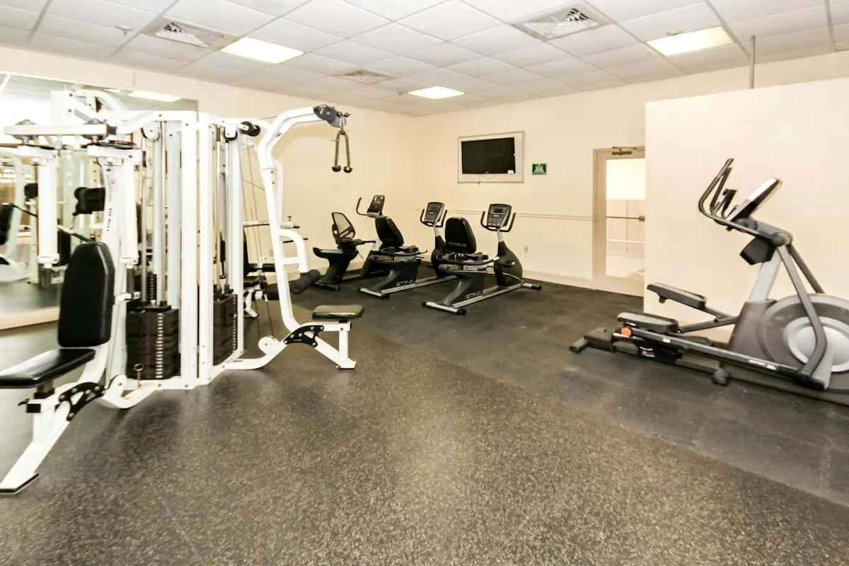 Un gimnasio con máquinas de ejercicio y equipos cardiovasculares.