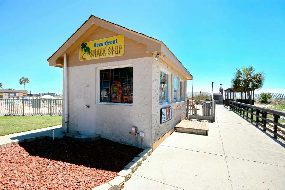 Una pequeña tienda de refrigerios está junto a un camino pavimentado y una baranda.