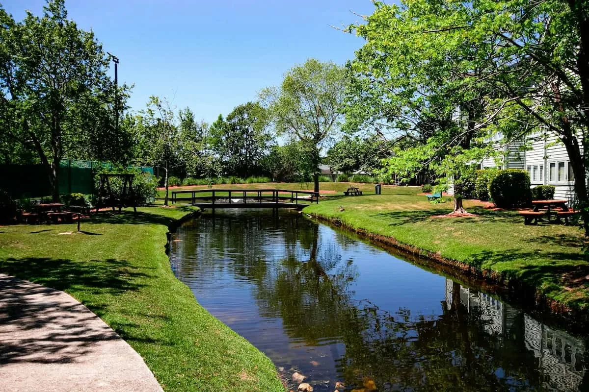 Un jardín cuidado con un estanque y un pequeño puente peatonal.