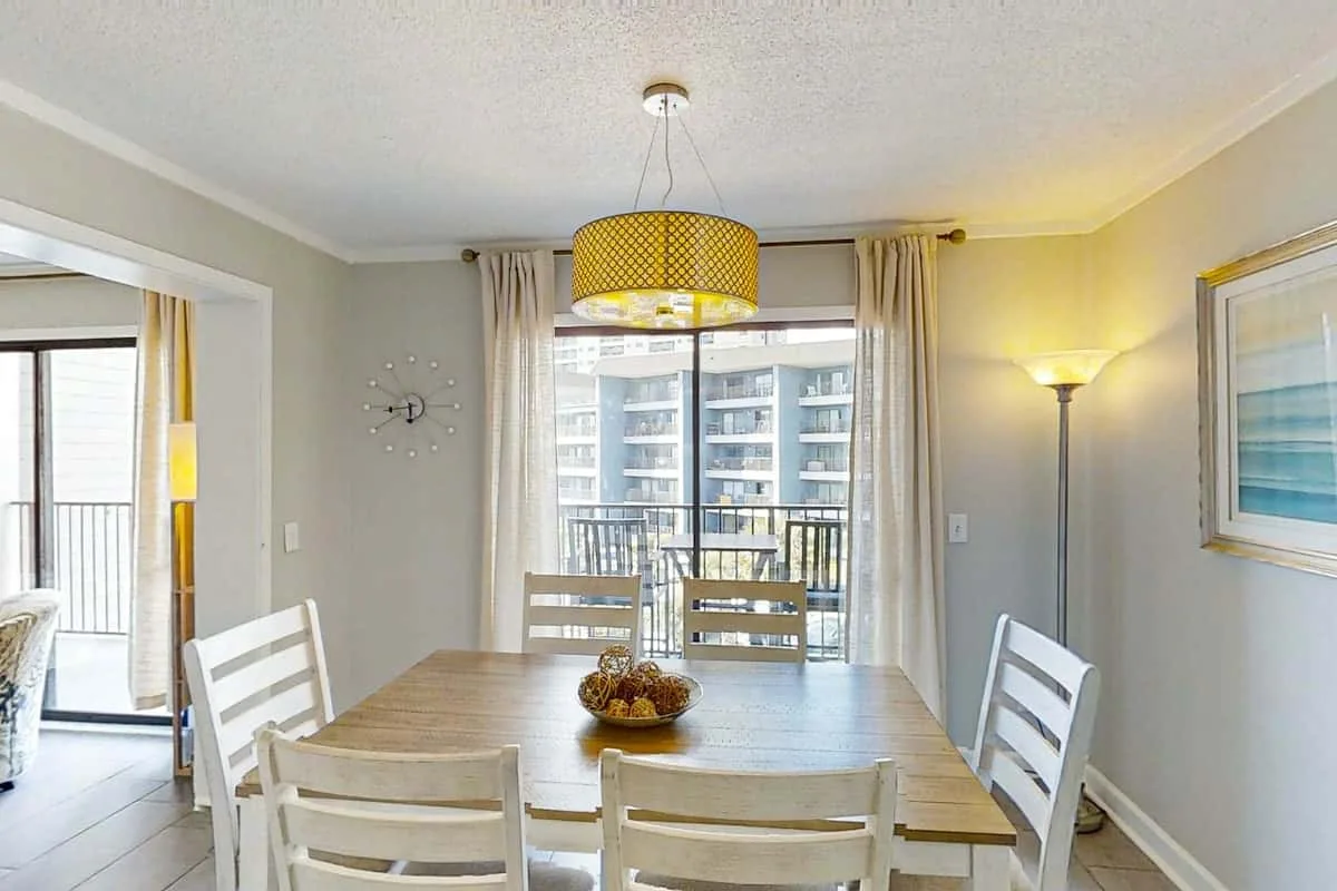 A dining area with a wooden table and chairs beside a large window.