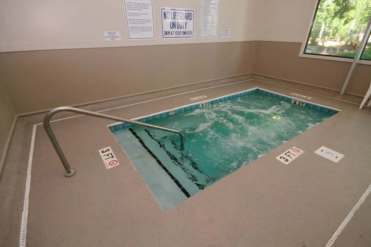 Una piscina cubierta con una barandilla metálica y avisos de seguridad en la pared.