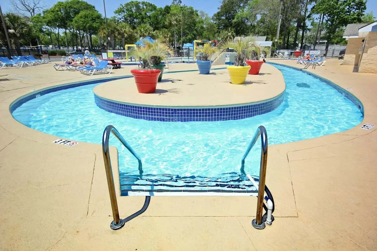 Una piscina al aire libre rodea una isla central con macetas de colores.